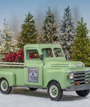 Life-size iron pickup truck in soft green with decimal on a passenger door and red Christmas plants in trunk