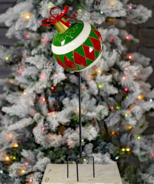 Large Metal Christmas Ball ornament on a tall stake in front of light-up Christmas tree